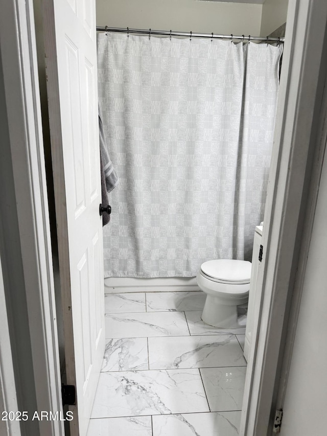 bathroom with marble finish floor, toilet, and a shower with shower curtain