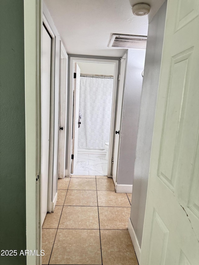 corridor featuring light tile patterned floors and baseboards