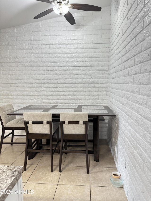 dining space with brick wall and light tile patterned flooring