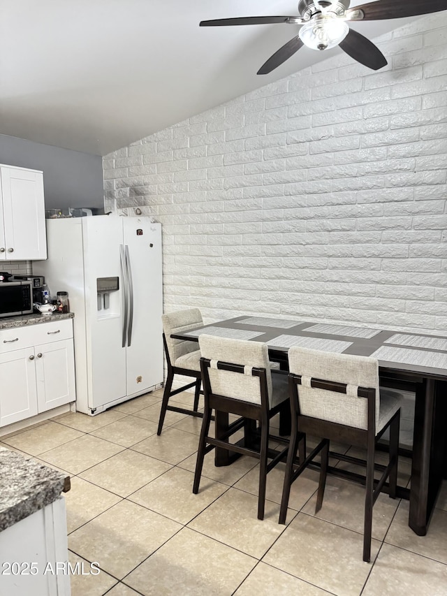 dining room featuring light tile patterned floors and brick wall