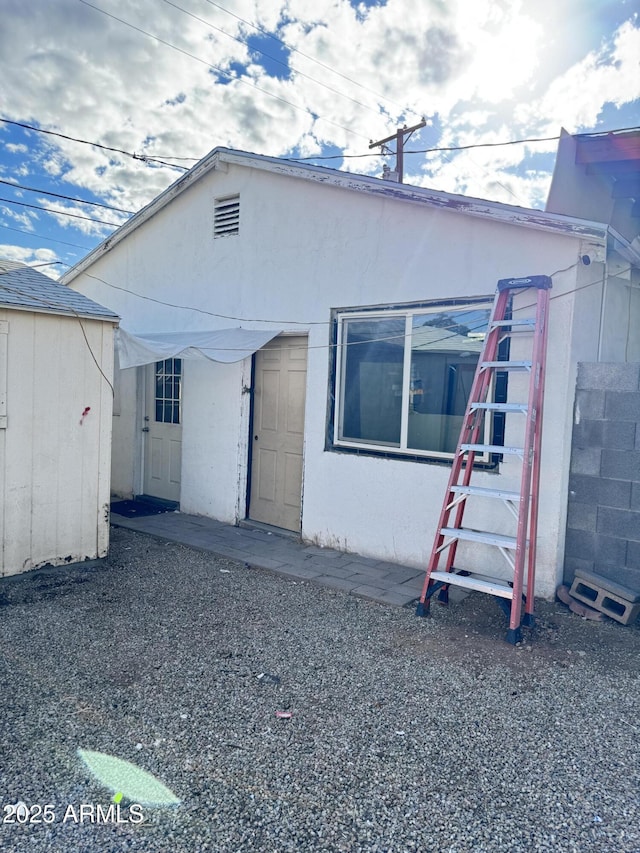 rear view of property featuring stucco siding and an outbuilding