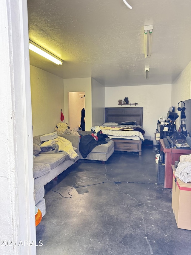 bedroom with a textured ceiling, concrete flooring, and a garage