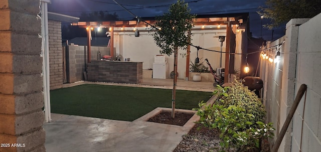 yard at twilight featuring fence and a patio area