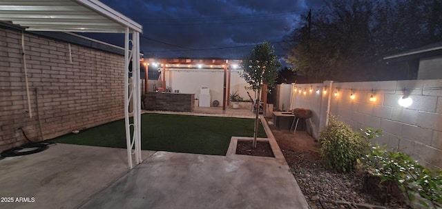 patio at night featuring a fenced backyard