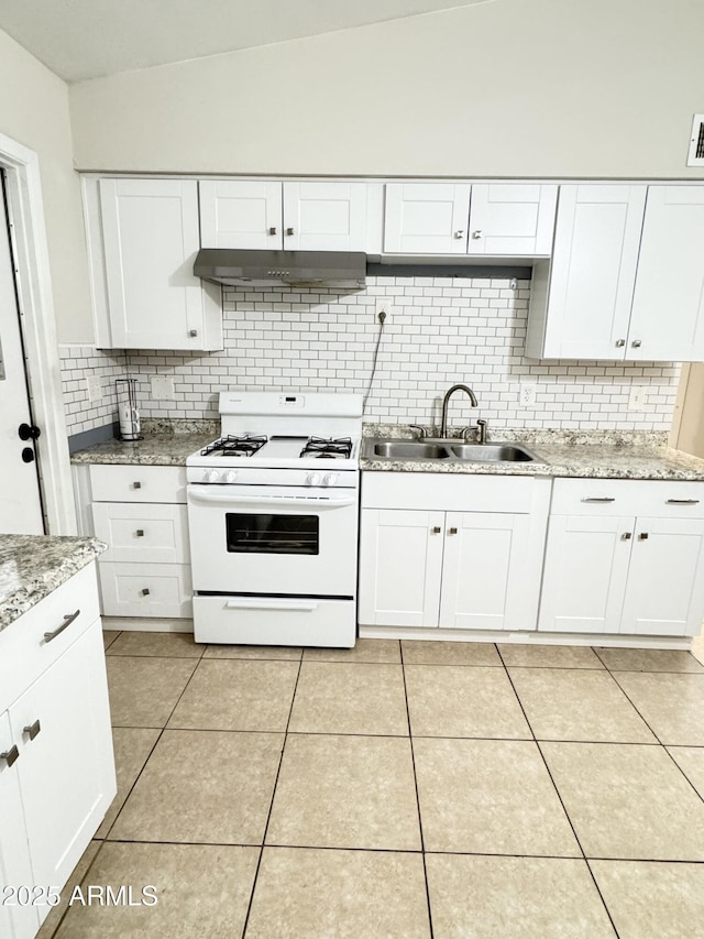 kitchen with light tile patterned floors, a sink, white gas range oven, under cabinet range hood, and white cabinetry