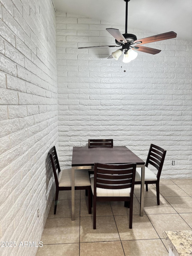 dining space featuring light tile patterned floors and brick wall