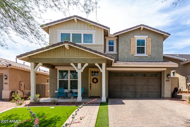 2562 N Springfield St, Buckeye, AZ 85396 - view of front of property with covered porch, decorative driveway, a garage, stucco siding, and board and batten siding