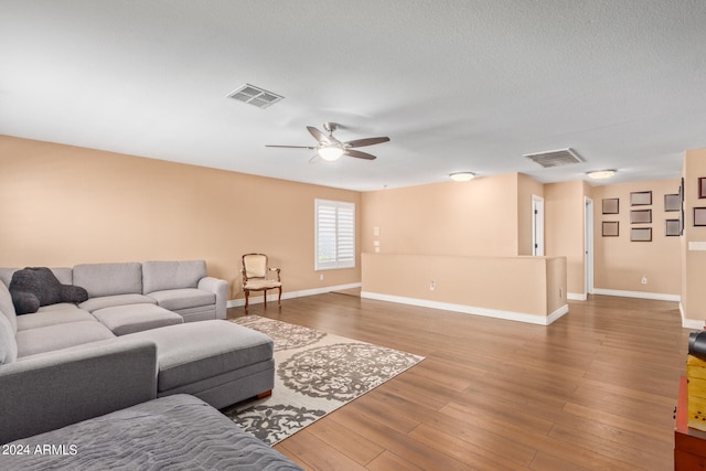 living room with ceiling fan, wood-type flooring, and a textured ceiling