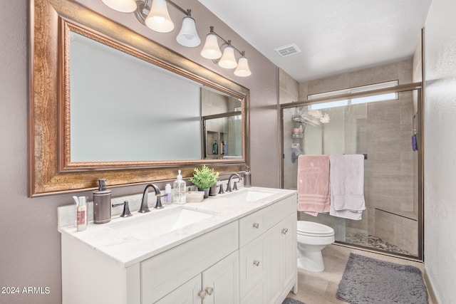 bathroom featuring vanity, a textured ceiling, toilet, and a shower with door