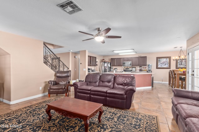 living room with a textured ceiling, light tile patterned floors, and ceiling fan with notable chandelier