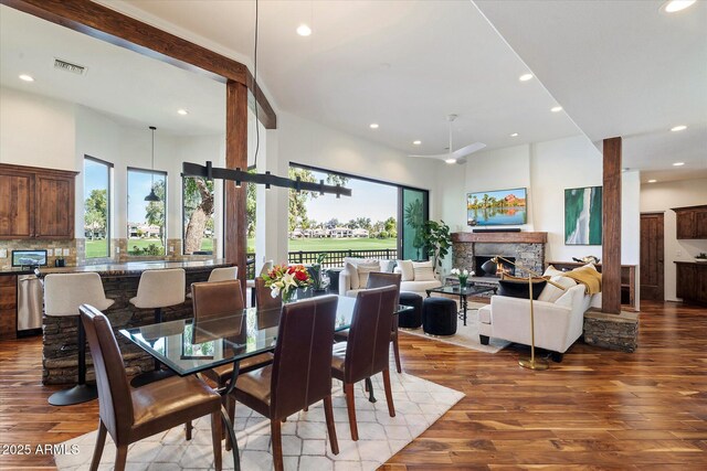 7272 E Gainey Ranch Rd Unit 29, Scottsdale, AZ 85258 - dining room featuring recessed lighting, wood finished floors, a stone fireplace, a ceiling fan, and a towering ceiling