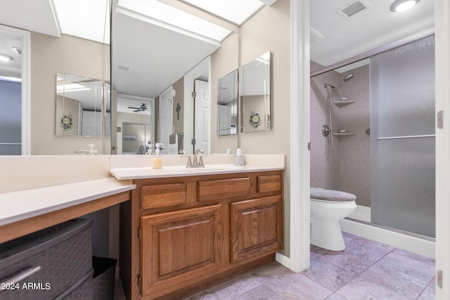 bathroom featuring ceiling fan, toilet, a shower with shower door, vanity, and tile patterned floors