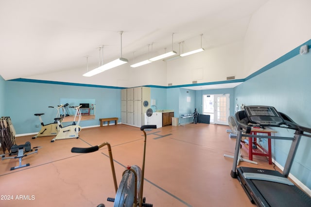 exercise room with concrete flooring and high vaulted ceiling