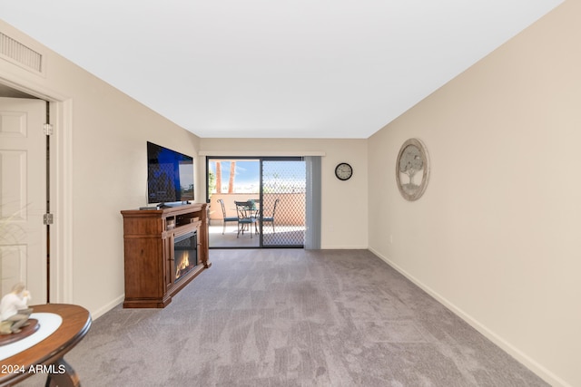 17404 N 99th Ave Unit 108, Sun City, AZ 85373 - unfurnished living room featuring carpet floors, baseboards, and a glass covered fireplace