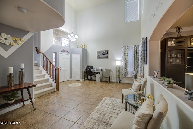 entrance foyer featuring baseboards, stairs, a towering ceiling, and an inviting chandelier