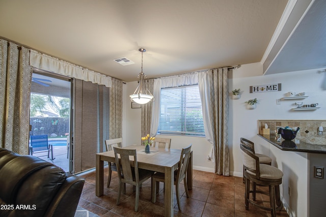 dining area featuring dark tile patterned floors, baseboards, and visible vents