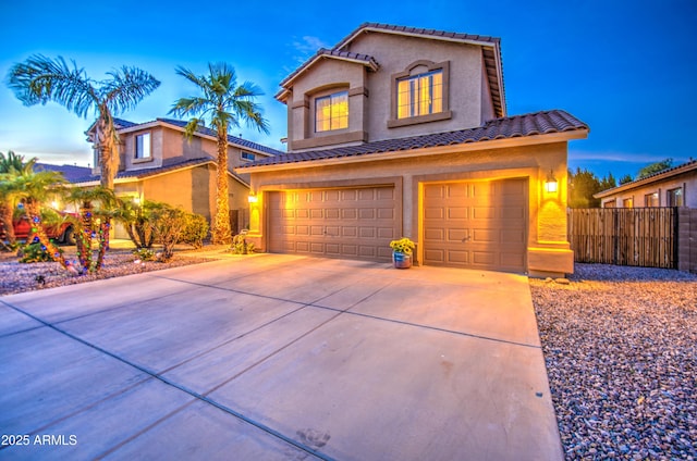 view of front of home featuring concrete driveway, stucco siding, fence, a tiled roof, and a garage