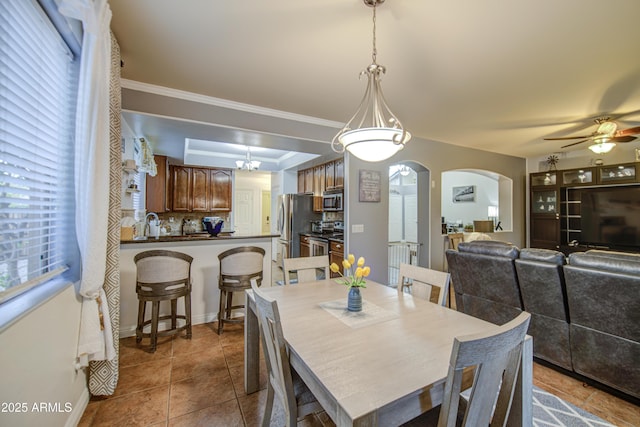 dining room featuring plenty of natural light, ceiling fan with notable chandelier, arched walkways, and a raised ceiling