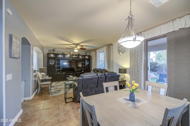 dining room featuring visible vents, baseboards, ceiling fan, arched walkways, and light tile patterned floors