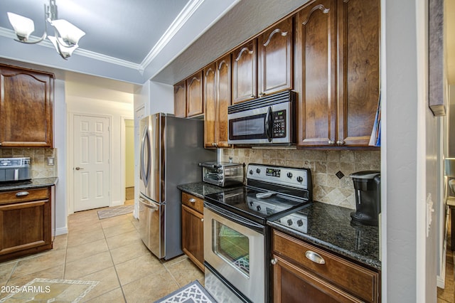 kitchen with light tile patterned floors, ornamental molding, stainless steel appliances, dark stone countertops, and a notable chandelier