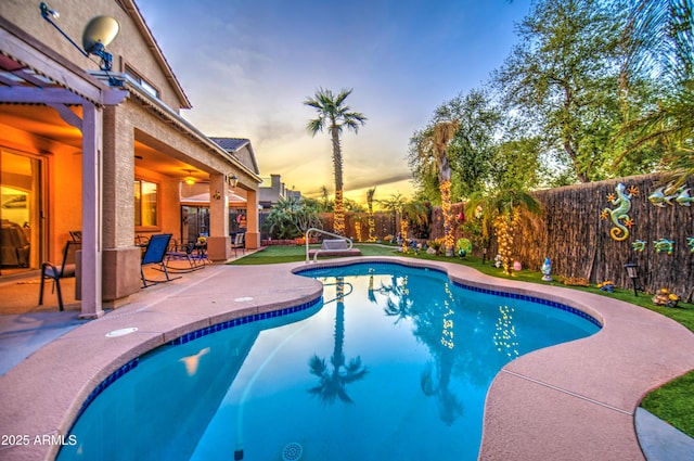 pool at dusk featuring a fenced in pool, a fenced backyard, and a patio area