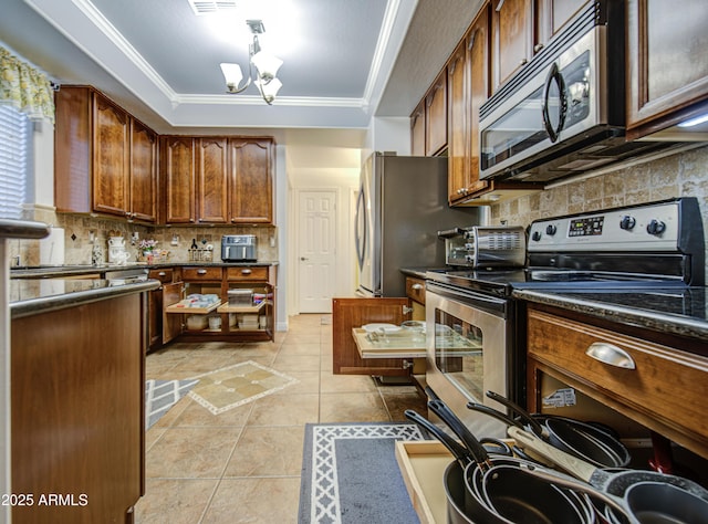 kitchen with ornamental molding, dark countertops, tasteful backsplash, appliances with stainless steel finishes, and light tile patterned floors