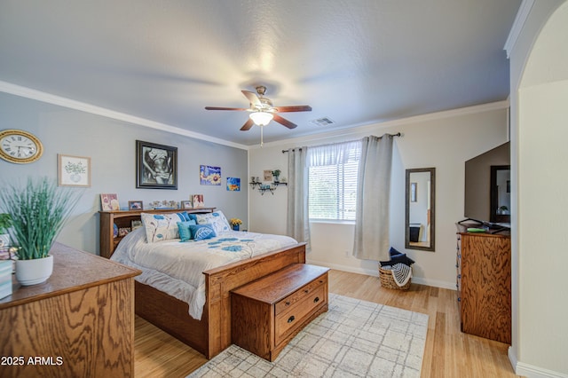 bedroom featuring baseboards, light wood-style flooring, visible vents, and crown molding
