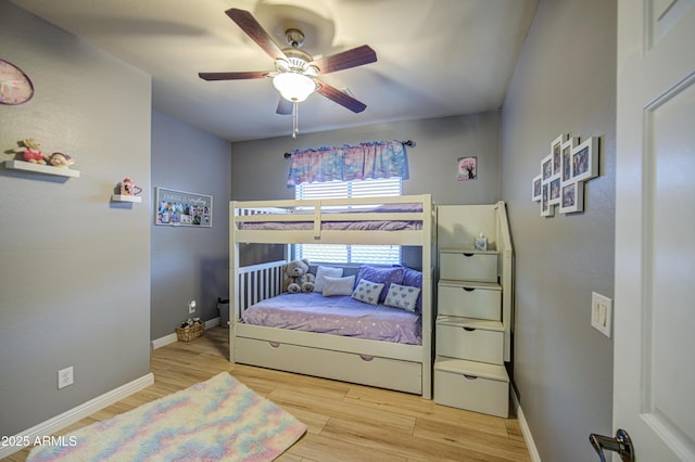 bedroom featuring baseboards, wood finished floors, and a ceiling fan