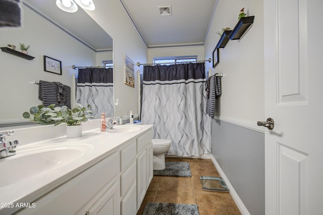 bathroom featuring tile patterned floors, toilet, double vanity, and a sink