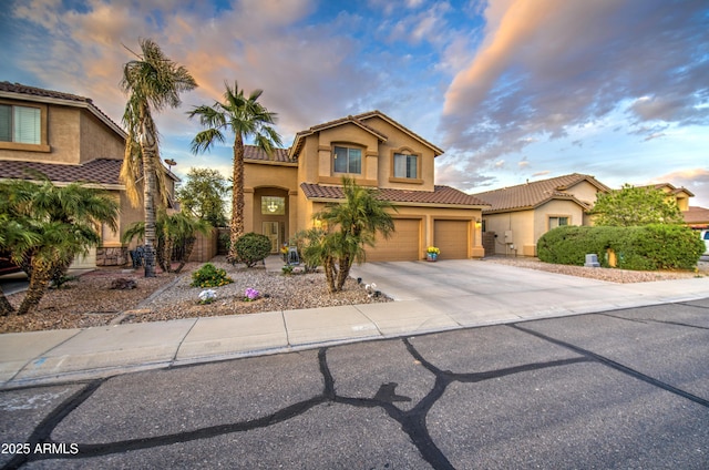 mediterranean / spanish-style house featuring a tile roof, concrete driveway, stucco siding, and an attached garage