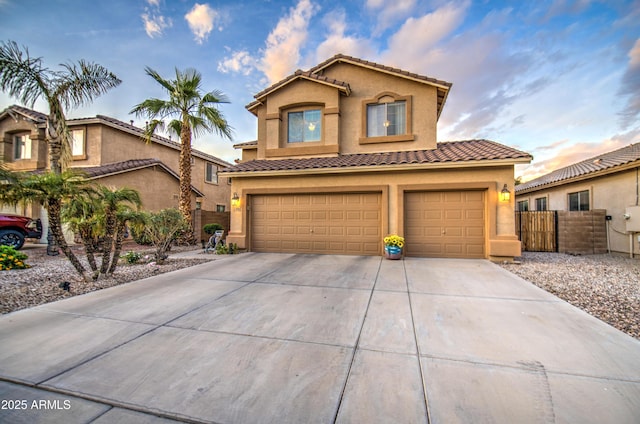 mediterranean / spanish home featuring fence, a tile roof, stucco siding, and a garage