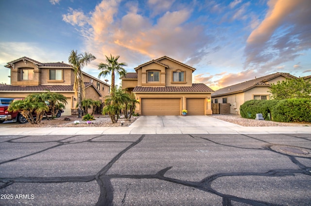 view of front of property featuring driveway, a garage, a tiled roof, and stucco siding