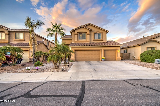 mediterranean / spanish-style home featuring a tiled roof, concrete driveway, stucco siding, and an attached garage