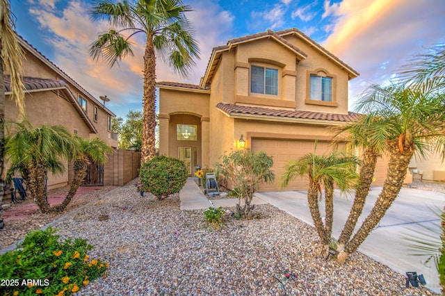 mediterranean / spanish home featuring stucco siding, a tiled roof, a garage, and concrete driveway