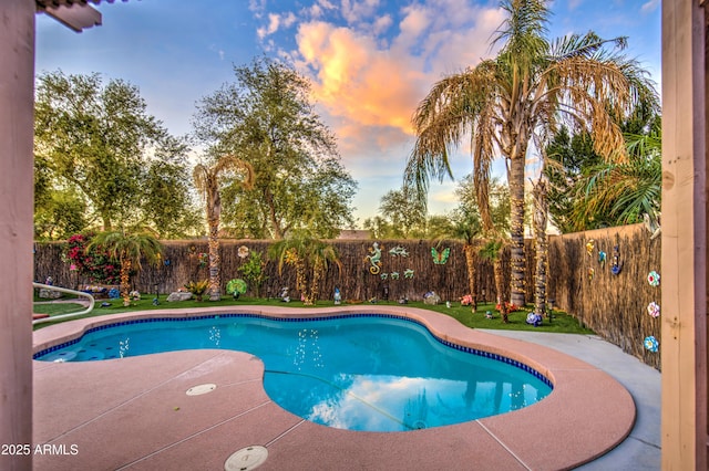 pool at dusk featuring a fenced in pool, a fenced backyard, and a patio area
