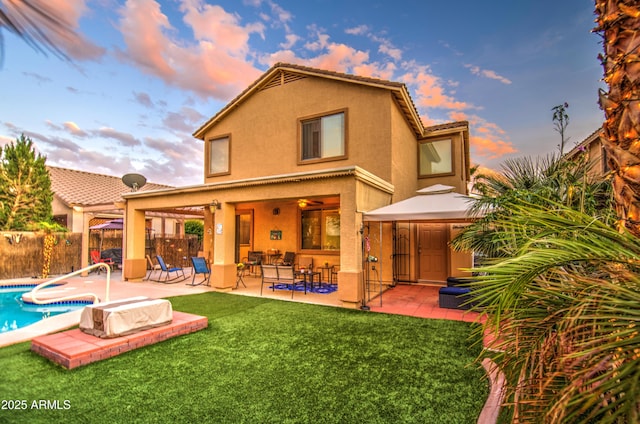 back of property featuring stucco siding, fence, a patio, a fenced in pool, and a lawn