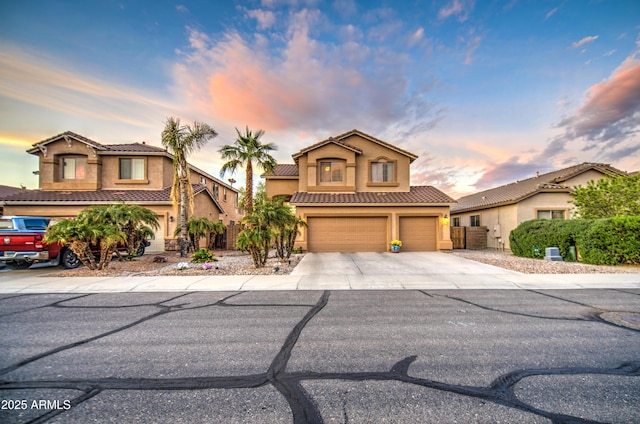 view of front facade with a tile roof, stucco siding, a garage, and concrete driveway