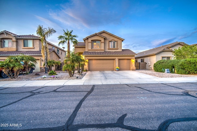 view of front of property featuring a tiled roof, stucco siding, driveway, and a garage