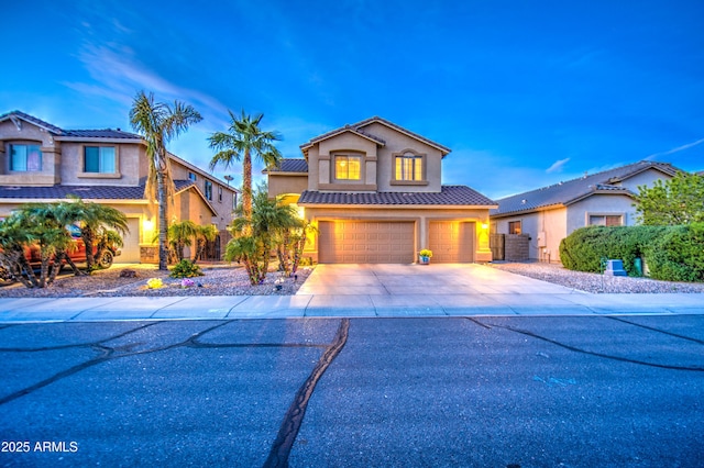 view of front of home with a tiled roof, stucco siding, driveway, and a garage