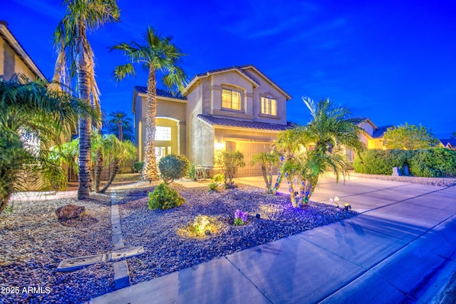 mediterranean / spanish house featuring driveway, a tile roof, a garage, and stucco siding
