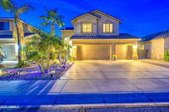 view of front facade with a tiled roof, stucco siding, concrete driveway, and a garage
