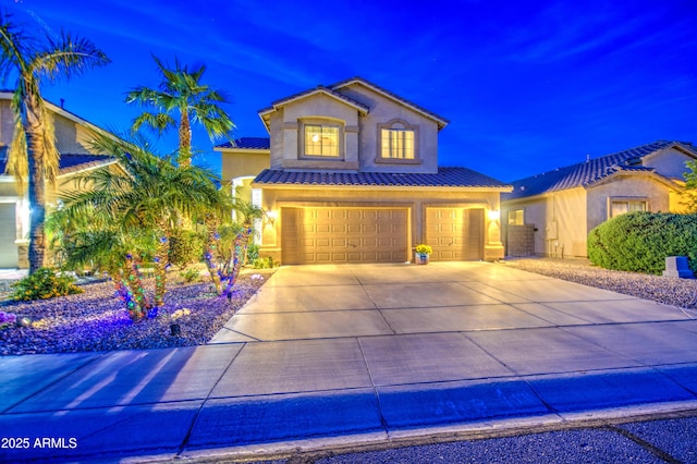 mediterranean / spanish-style house with a tiled roof, stucco siding, an attached garage, and concrete driveway