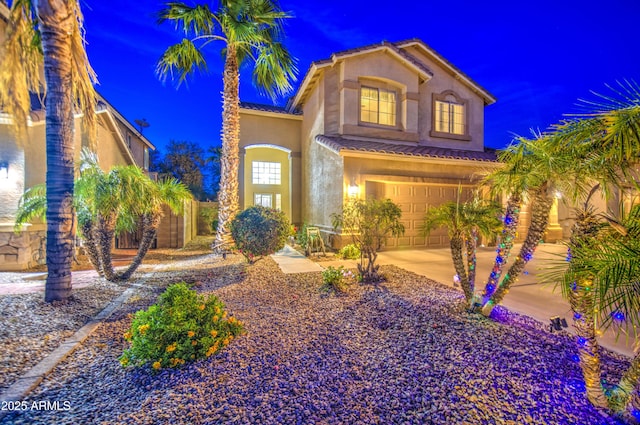 mediterranean / spanish-style home with an attached garage, a tile roof, concrete driveway, and stucco siding
