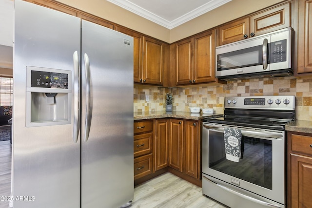 4601 N 102nd Ave Unit 1055, Phoenix, AZ 85037 - kitchen featuring appliances with stainless steel finishes, crown molding, brown cabinetry, light wood-style flooring, and decorative backsplash