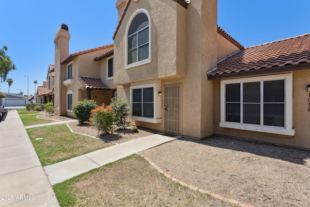 4601 N 102nd Ave Unit 1055, Phoenix, AZ 85037 - view of front of home featuring stucco siding, a tiled roof, and a chimney