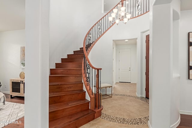 stairway featuring a towering ceiling and a chandelier