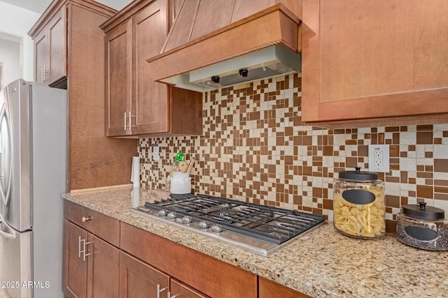 kitchen with stainless steel appliances, tasteful backsplash, light stone countertops, and custom exhaust hood