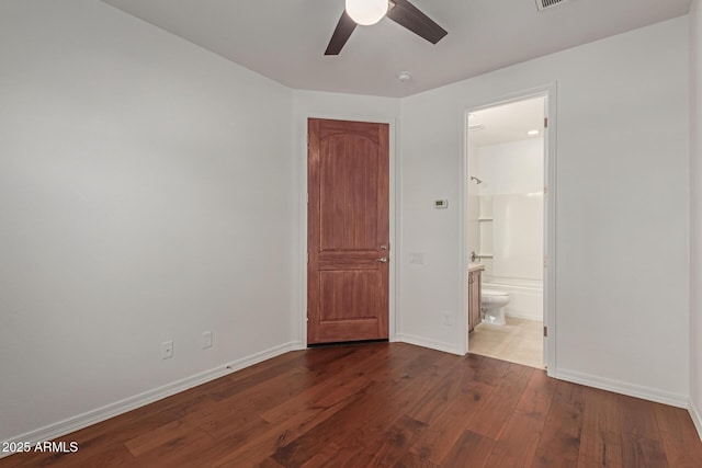 unfurnished bedroom with ensuite bath, dark hardwood / wood-style floors, and ceiling fan