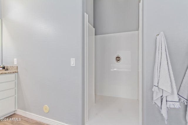 bathroom featuring hardwood / wood-style floors, vanity, and a shower