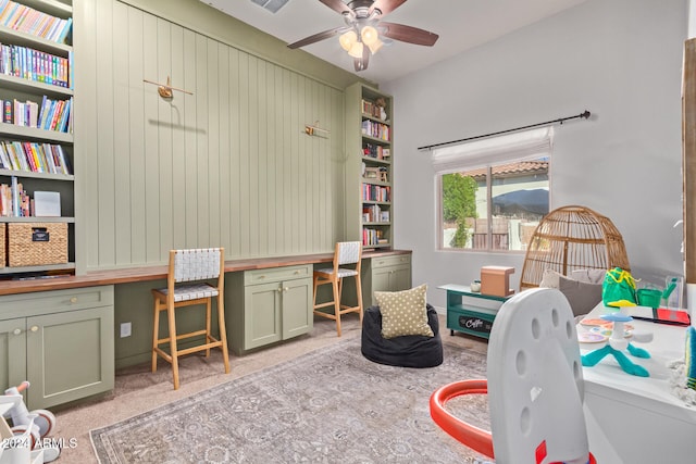 office area with ceiling fan, built in desk, and light colored carpet